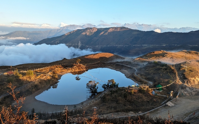       A serene landscape with a reflective pond and mountains in the background.
  