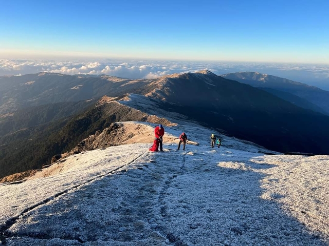 Hikers trekking on a snow-covered mountain ridge.