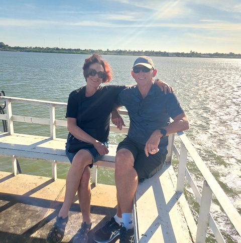Couple sitting on a boat with a large body of water in the background.