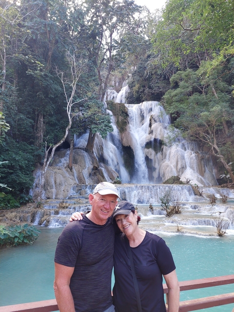       People posing in front of a waterfall in nature.
  