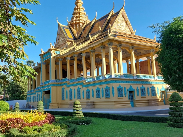       Large iconic building with intricate architecture and manicured garden.
  