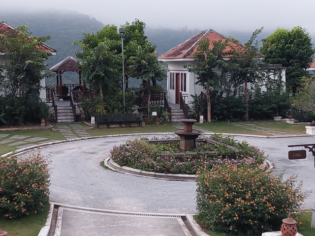 Circular garden with a fountain surrounded by quaint buildings.