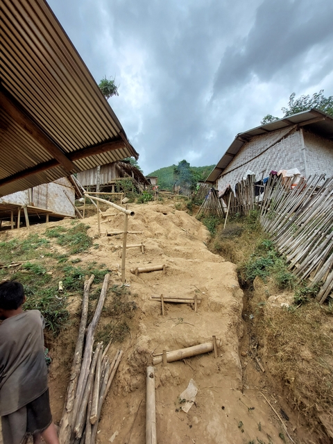 Rural village with bamboo structures on a hillside.