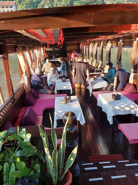       Indoor seating area on a boat with people dining.
  