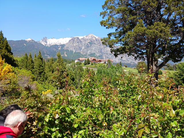       Mountains with snow caps and green foreground, a group of tourists visible.
  