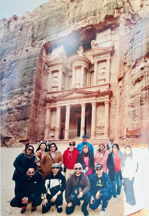       Group of tourists posing in front of the iconic Petra site.
  