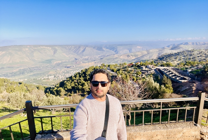       Individual taking a selfie with a scenic mountainous landscape.
  