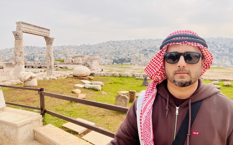       Individual standing near ancient ruins with a city view.
  