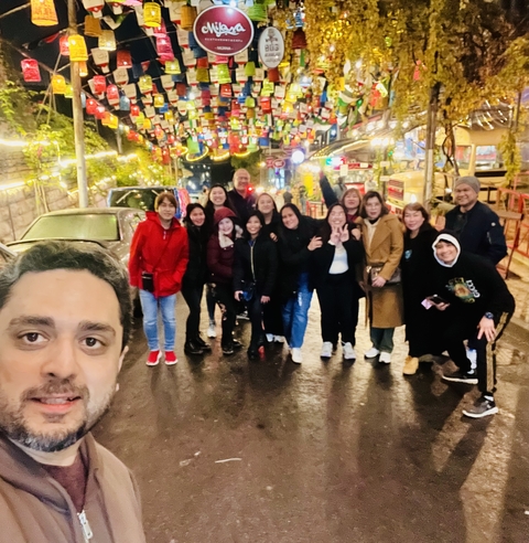 A group of people standing on an illuminated street with colorful decorations.