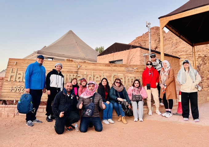       Group photo in front of a sign for a desert camp.
  