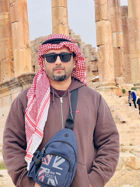       Person standing in front of ancient stone ruins.
  