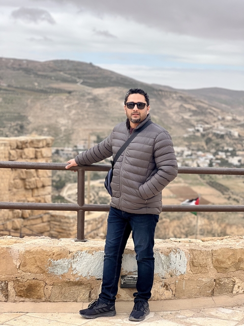       Individual posing on a balcony with a vast landscape view.
  