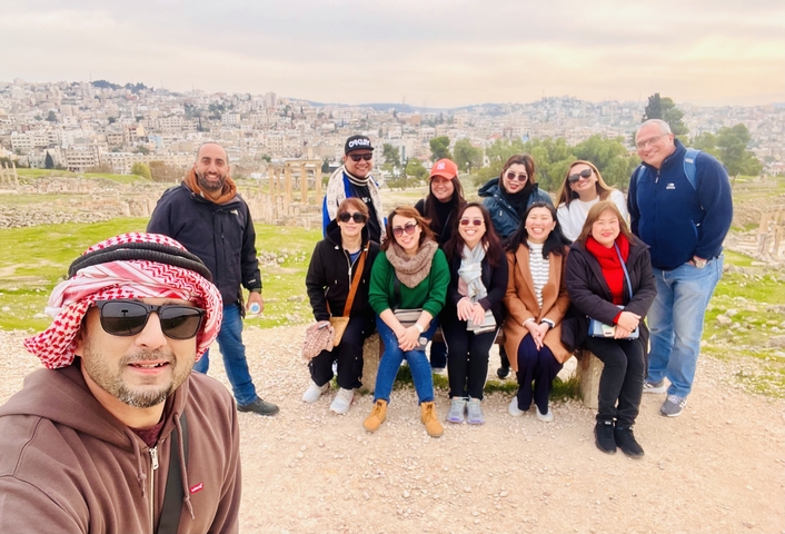 Group of tourists posing in front of a cityscape with ruins visible.