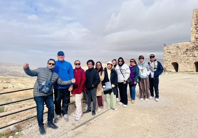       Group posing at a scenic overlook with ruins.
  