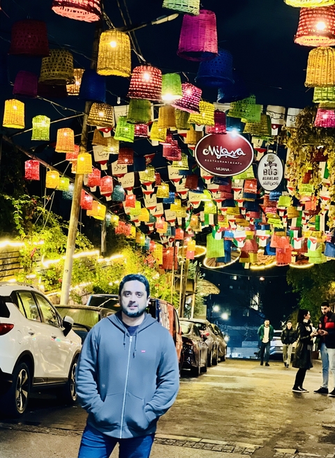       Person seen under vibrant hanging decorations with night lighting.
  