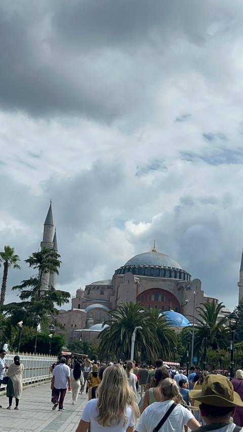       Tourist area with a large historic building and a crowd.
  