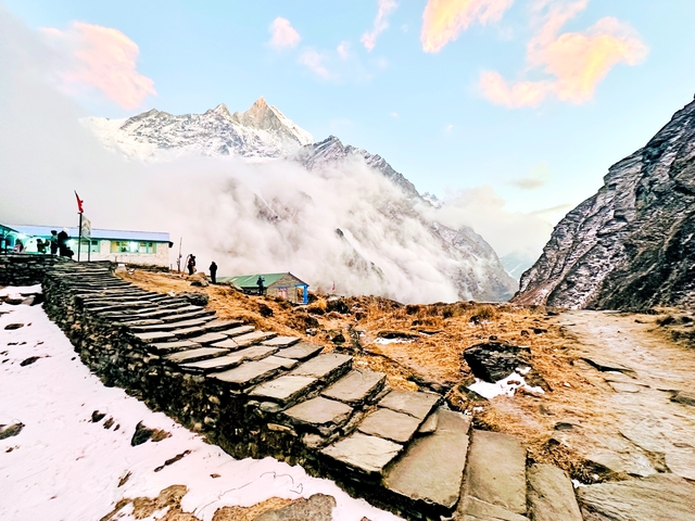       Pathway leading through a mountainous landscape with people and fog.
  
