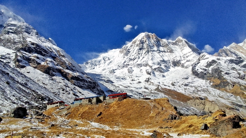       Snow-capped mountains with small buildings in a rugged landscape.
  