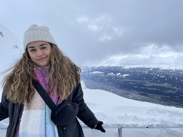 Woman smiling in a snowy mountain landscape.