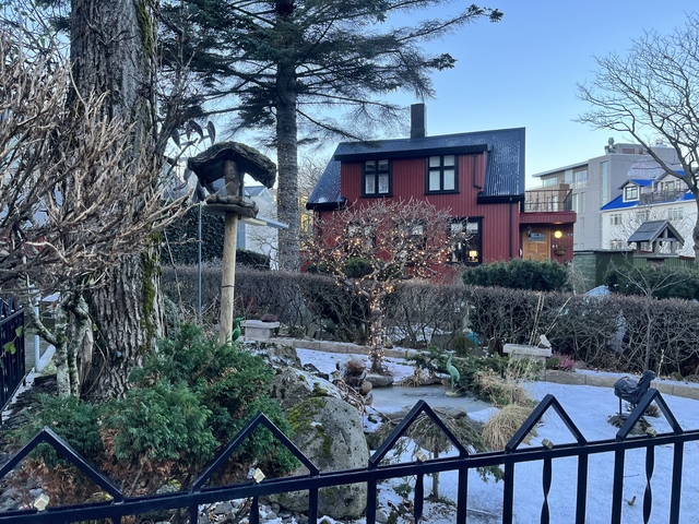 Red house in a garden with winter frost visible.