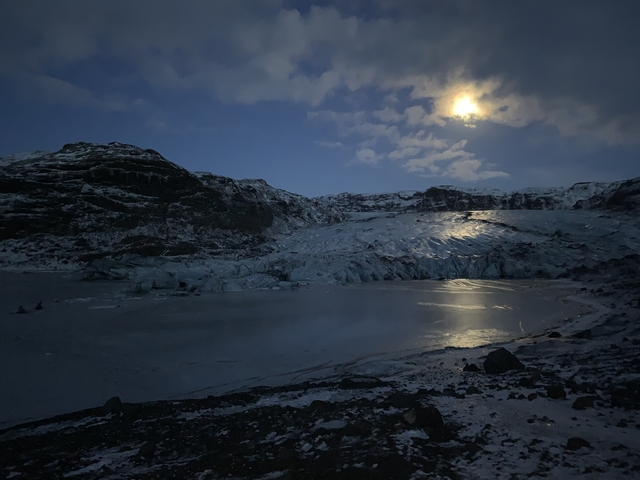 Nighttime view of a glacier under a bright moon.