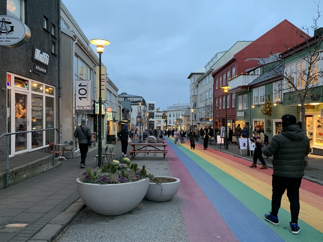 Colorful pedestrian street in a city with people walking, surrounded by buildings.