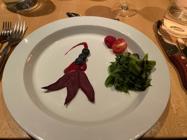 Gourmet salad with beetroot, greens, and berries artfully arranged on a plate.