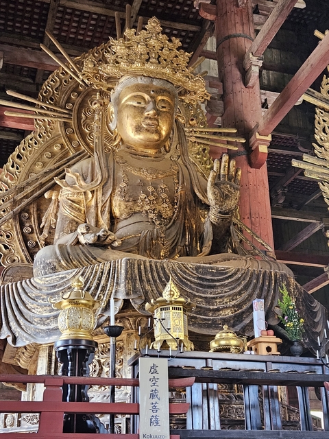       A large golden Buddha statue in a temple setting.
  