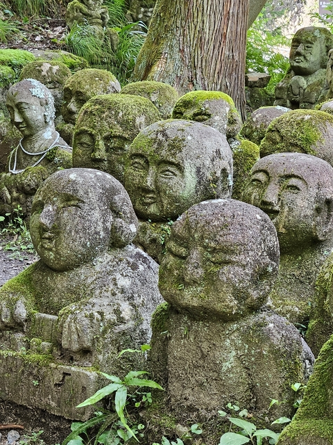 Stone figures with moss on them set in a garden.