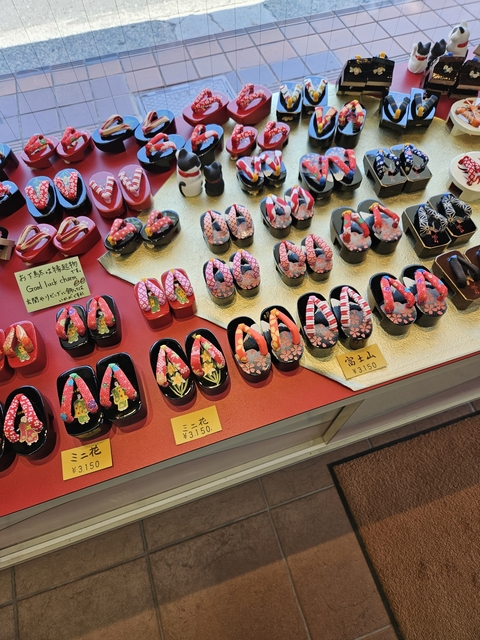 Miniature shoes on display with price tags.