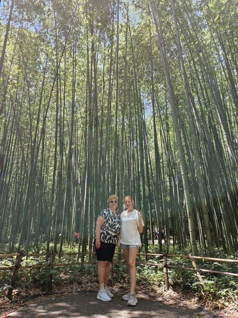       Two people standing in a lush bamboo forest.
  