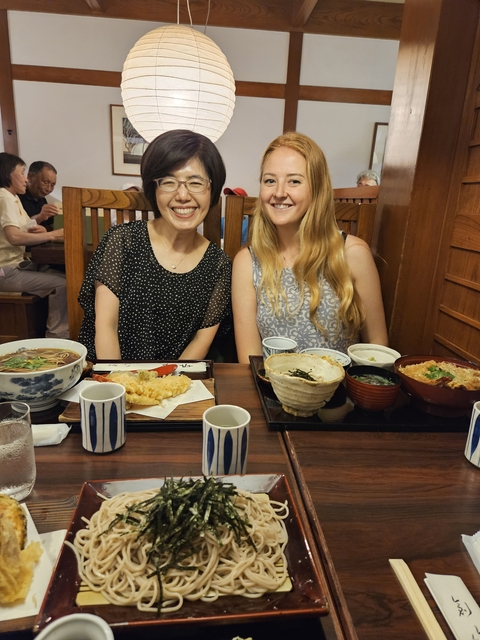       Two people smiling at a restaurant table with traditional Japanese dishes.
  