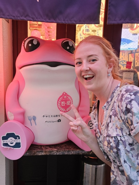 Person posing with a large cartoon character statue.