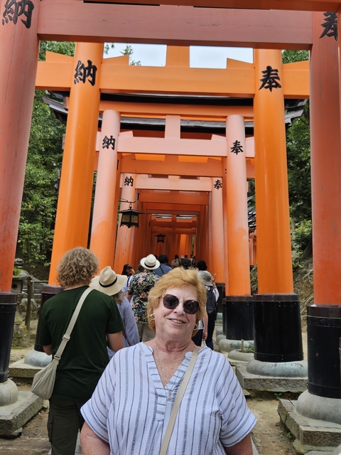       Bright orange Torii gates with tourists walking through.
  