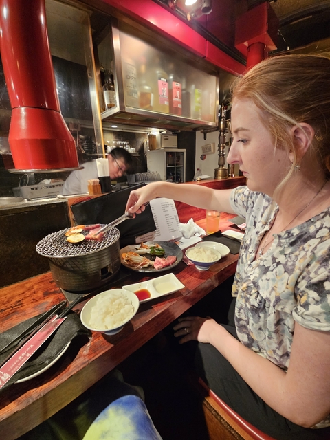       Person cooking meat on a small grill at a restaurant.
  
