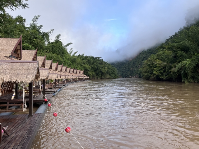 Scenic view of a river with floating huts against lush green hills.