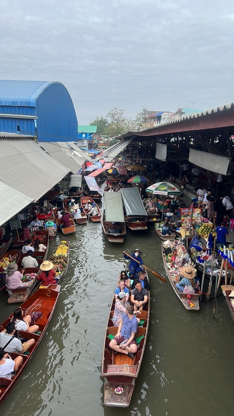 Busy floating market with boats and vendors selling goods.