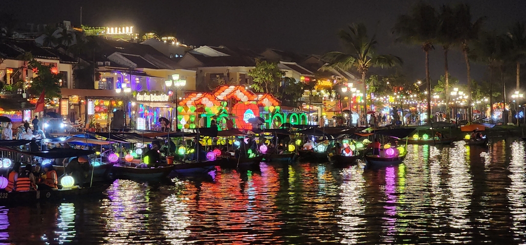 Boats with illuminated lanterns on a river at night.