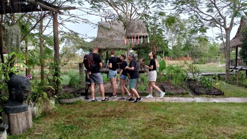 Group of people walking in a garden with traditional structures.