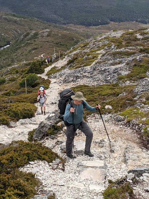 Hikers on a rocky trail in a mountainous region.
