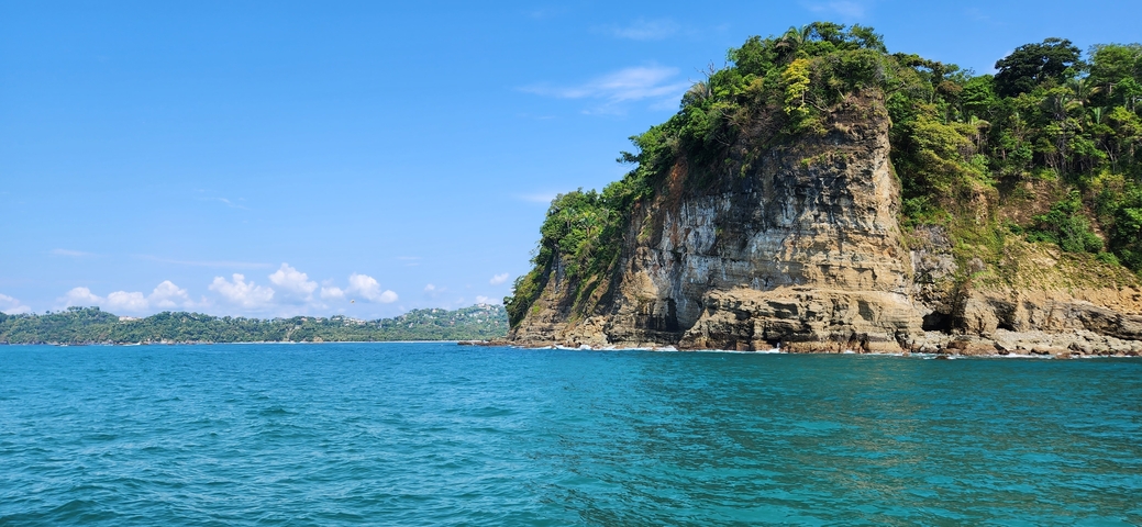Rocky cliffs with lush vegetation overlooking the sea.