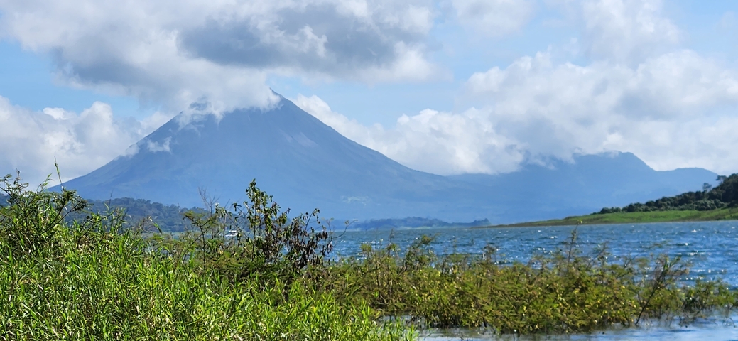 Volcano in the distance with a lake and vegetation.