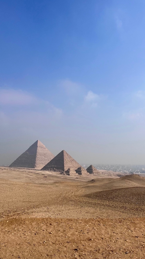       The Great Pyramids of Giza under a blue sky.
  