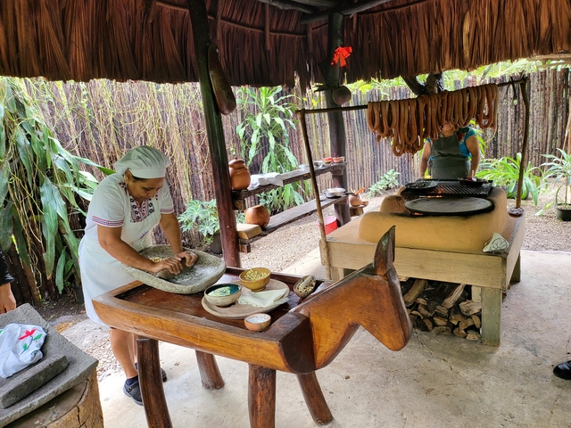 Two women preparing food in an outdoor kitchen setting.