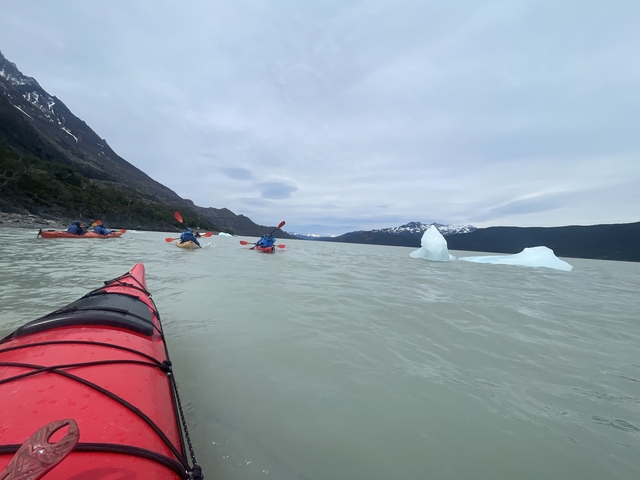       Kayakers paddling near ice formations in a glacial lake.
  