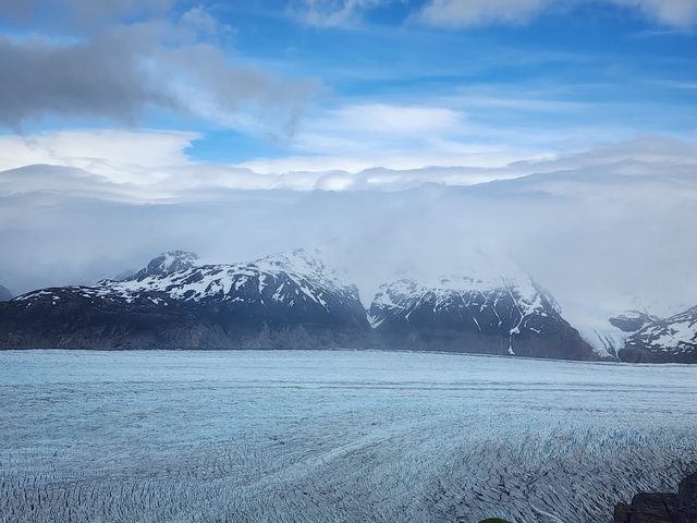 Glacier with mountains partly covered by clouds.