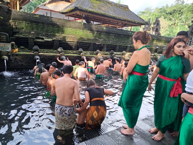 People gathering in a temple pool wearing green dresses.