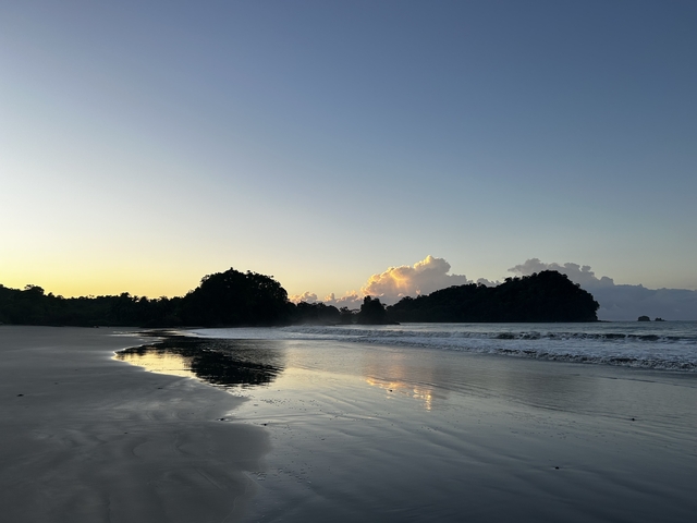       Calm beach at sunset with waves lapping against the shore.
  