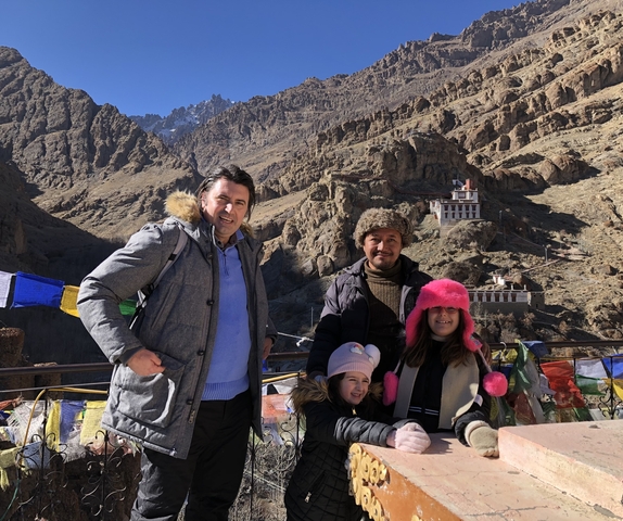       Group of tourists with a monastery and mountains in the background.
  