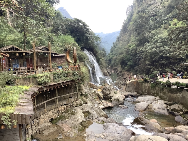 Waterfall with wooden structures and tourists.
